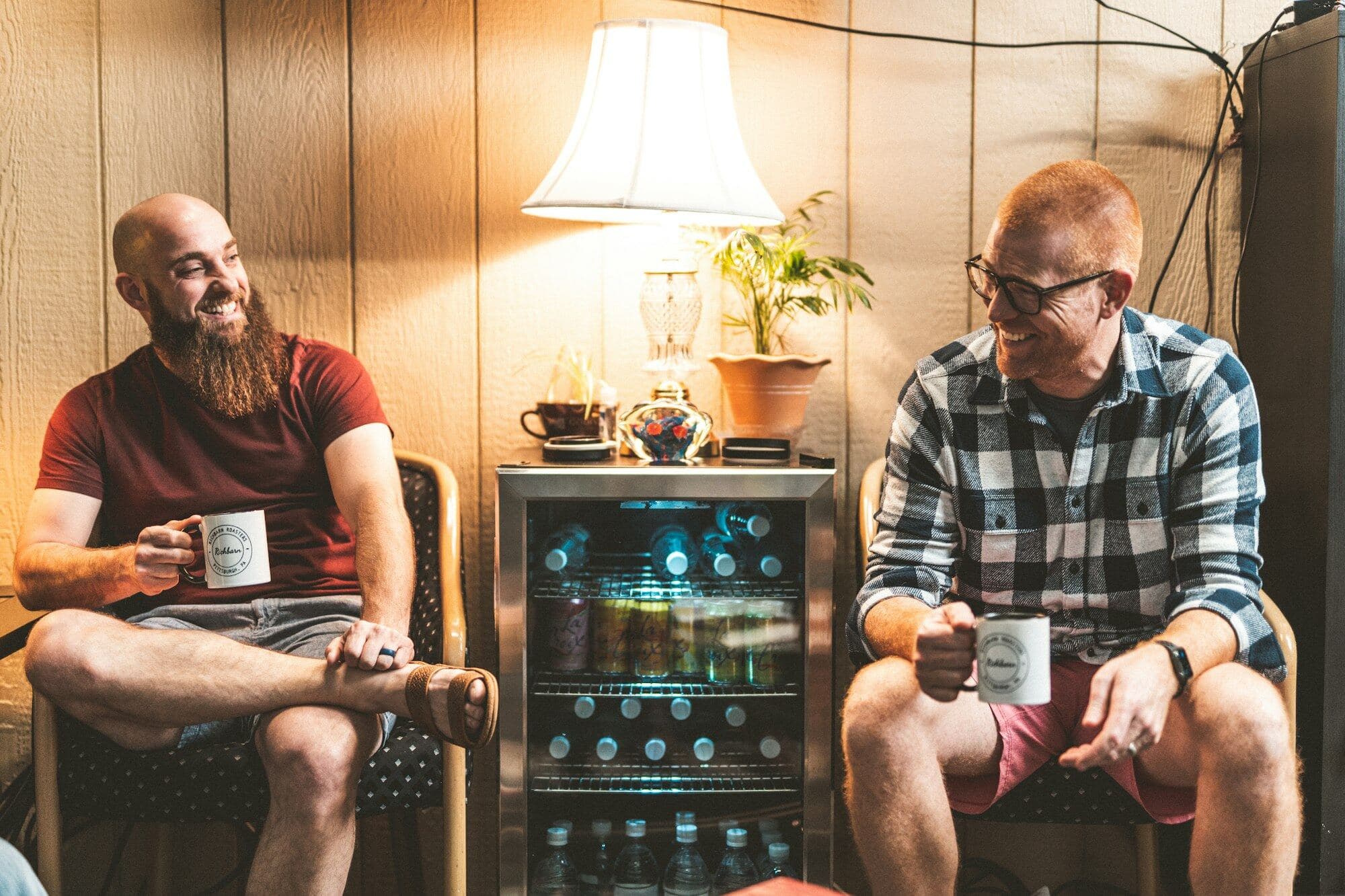 Dos amigos conversan relajados con un café