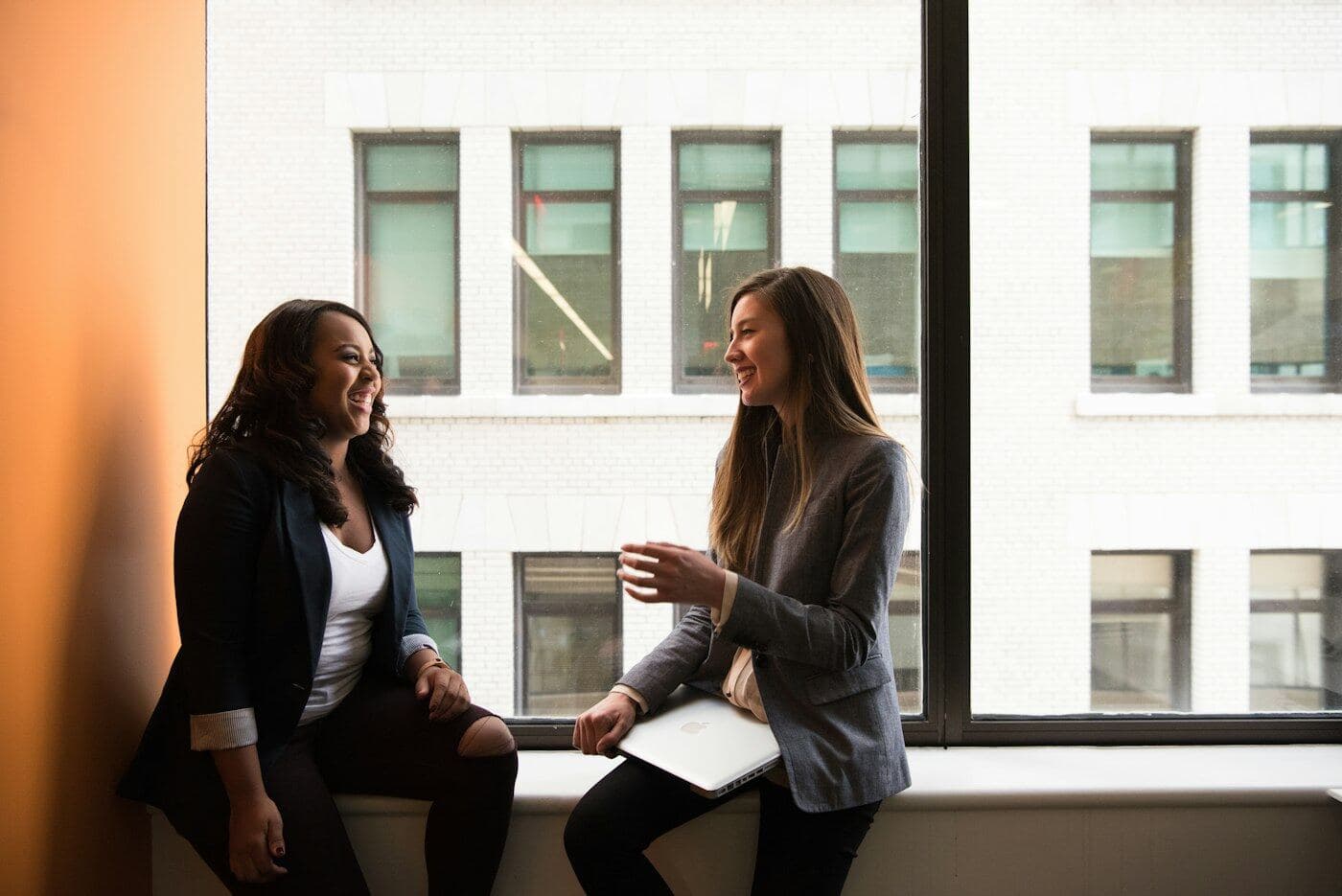 Dos mujeres conversan junto a una ventana